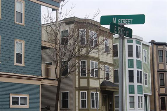 Front view of a multi-story house with street signs in the foreground.