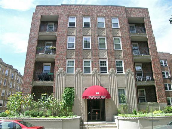 Front view of a multi-story apartment building with a brick facade and balconies.