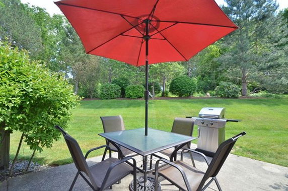 Outdoor patio area with a table, chairs, umbrella, and a grill.