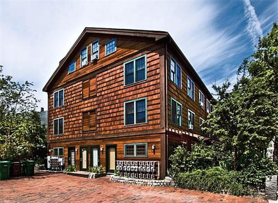 Front view of a multi-story wooden house with multiple windows.