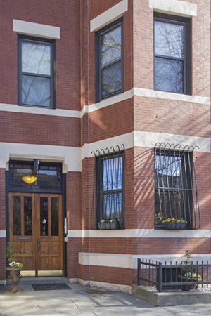 Front view of a brick building with decorative window bars and a wooden entrance door.