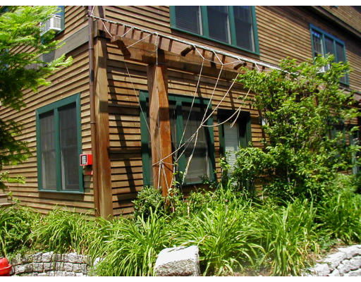 Front view of a house with wooden siding and a pergola structure.