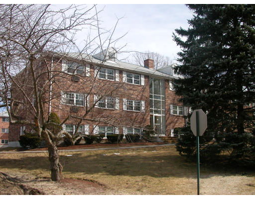 Front view of a multi-story brick building with multiple windows and a central glass entrance.