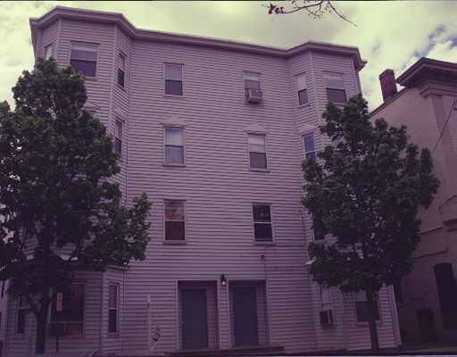 Front view of a three-story residential building with a flat roof and multiple windows.