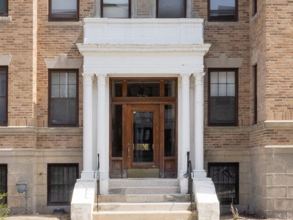 Front entrance of a brick building with white pillars and steps.