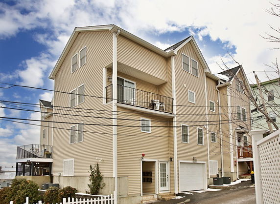 Front view of a multi-story residential building with a garage and balcony.