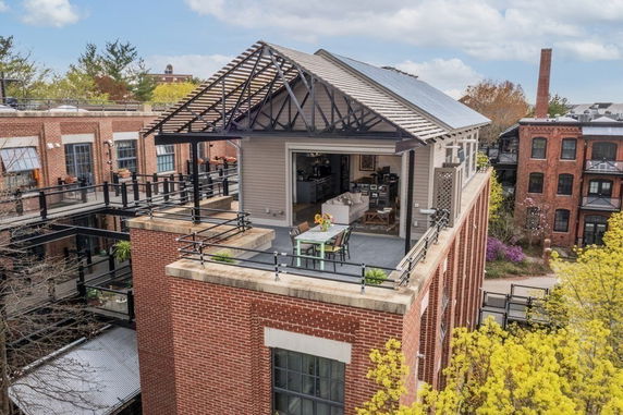 Rooftop view of a brick building with a seating area and open interior space.