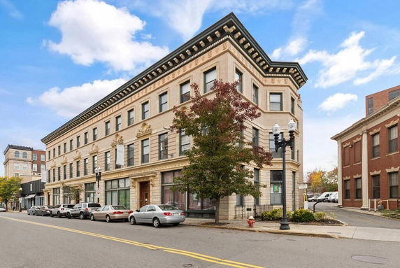 Front view of a three-story building with decorative architectural features and multiple windows lined along its facade.
