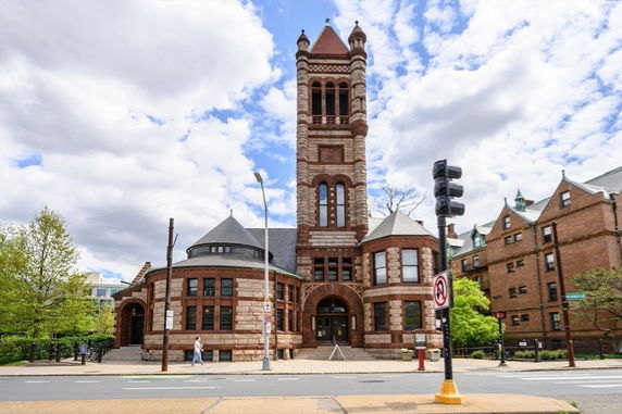 Front view of a historic building with a tall tower and arched entrance.