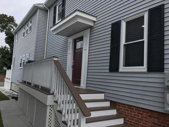 Side view of a house with a staircase and door.