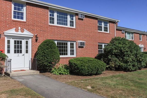 Front view of a two-story brick building with multiple windows and a white door.