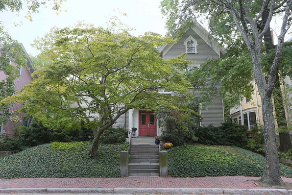 Front view of a two-story house with a gabled roof and red entrance door.