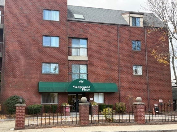 Front view of a multi-story brick building with a green awning entrance.