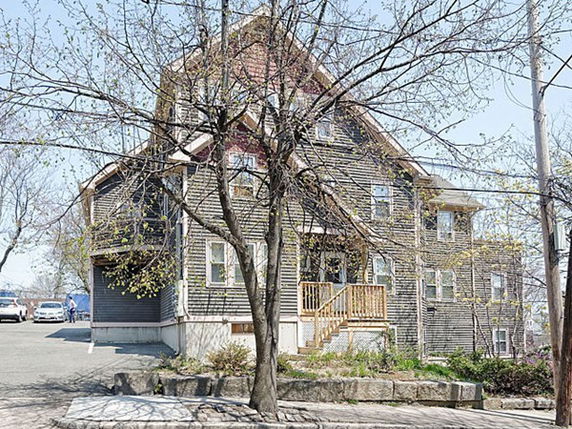 Front view of a multi-story house with a wooden exterior and multiple windows.