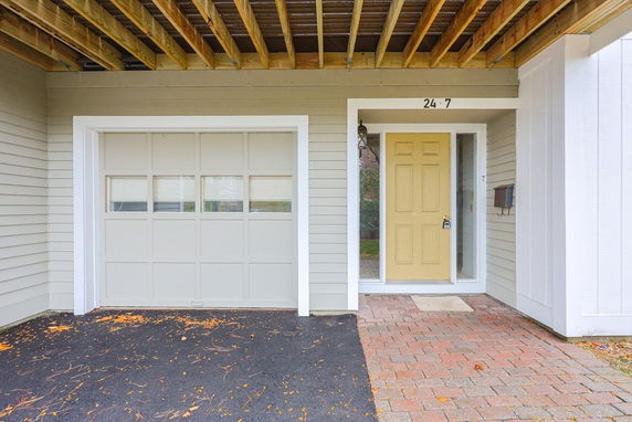 Front view of a building with a garage door and a yellow entrance door.
