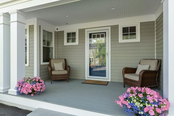 Front view of a house entrance with a porch and seating area.