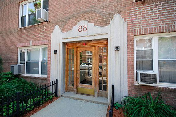 Front view of a brick building entrance with glass doors and number 88 above.