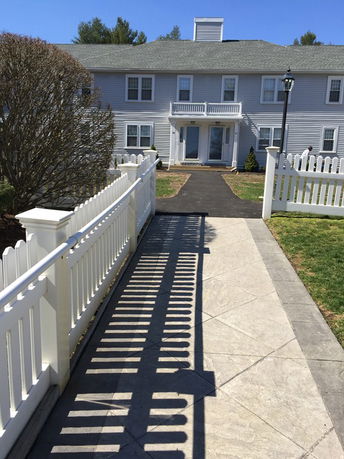Front view of a two-story house with a white fence and walkway.