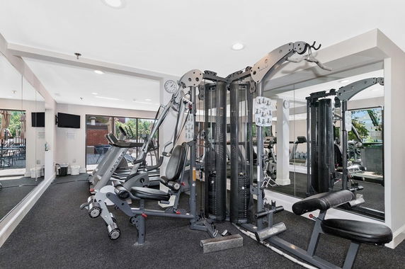 Interior view of a gym area equipped with exercise machines and mirrored walls.