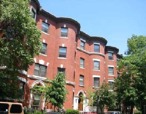 Front view of a multi-story brick residential building with multiple windows.