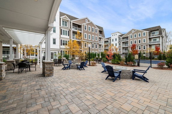 Front view of a multi-story residential building with outdoor seating area.