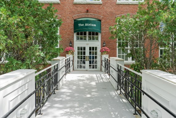 Front view of a building entrance with a canopy and a bridge leading to the door.