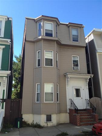 Front view of a multi-story house with bay windows and a small porch with steps.