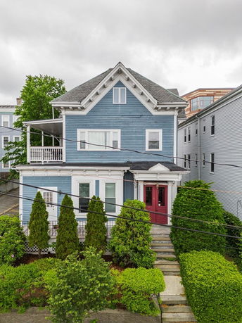 Front view of a two-story blue house with a porch and a gable roof.