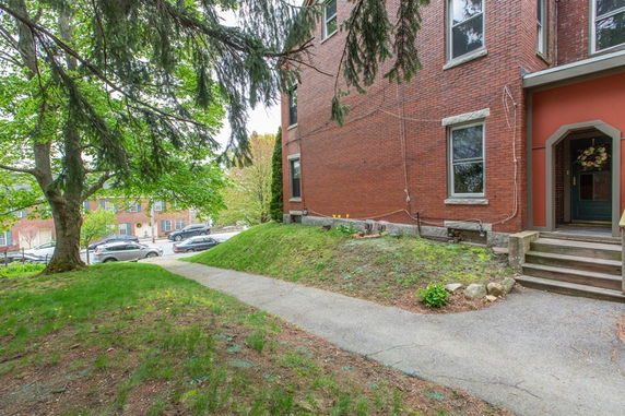 Side view of a brick building with steps leading to an entrance and a walkway.