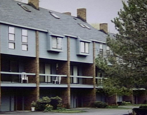 Front view of a multi-story residential building with balconies and a sloped roof.