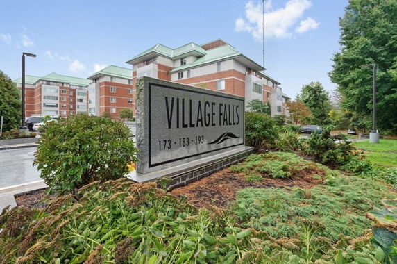 Front view of a multi-story apartment complex with a large sign reading 'Village Falls'.