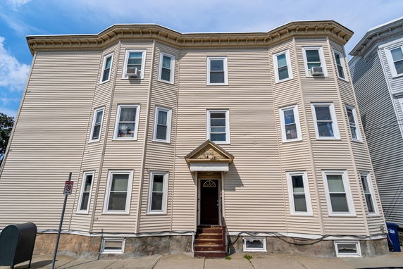 Front view of a three-story residential building with multiple windows and a central entrance.