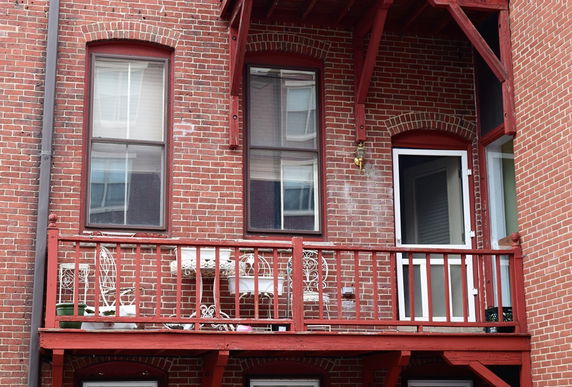 Front view of a brick building with a small balcony and windows.