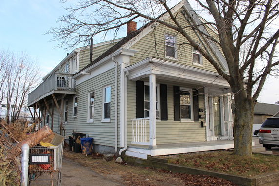 Front view of a two-story house with a porch and an elevated side deck.
