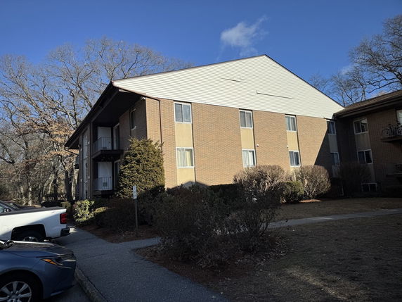 Front view of a multi-story apartment building with brick and siding exterior.