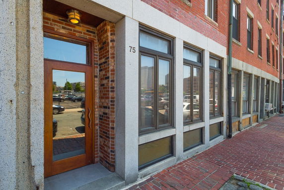 Front view of a brick building with large windows and a wooden door.