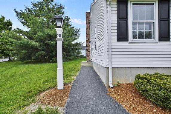 Side view of a house exterior showing a window with shutters and a lamp post with house number.