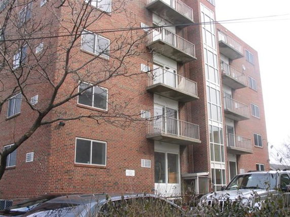 Front view of a multi-story brick apartment building with balconies.