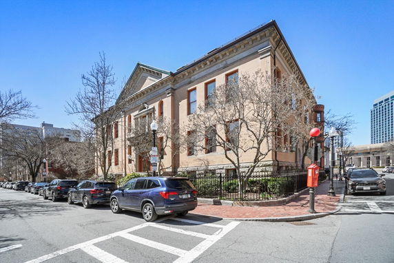 Front view of a two-story brick building with large windows and a gabled roof, located on a corner street.