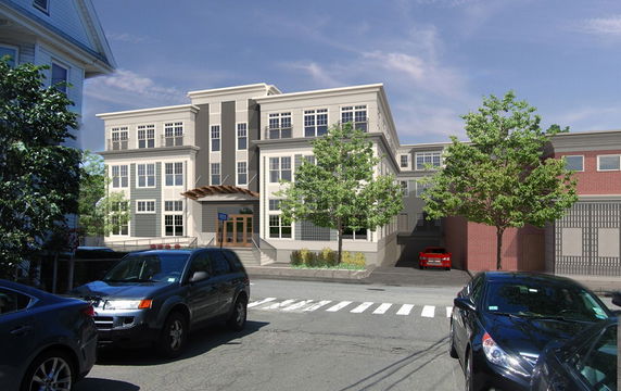 Front view of a multi-story building with large windows and a wooden canopy over the entrance.