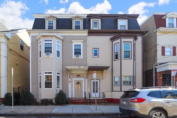 Front view of a multi-story house with bay windows.