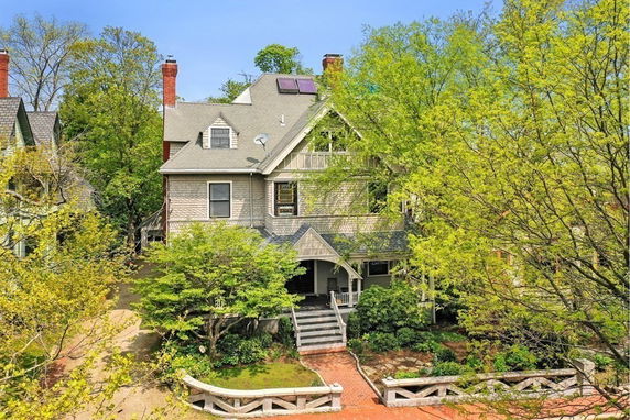 Front view of a multi-story house with a porch and solar panels on the roof.