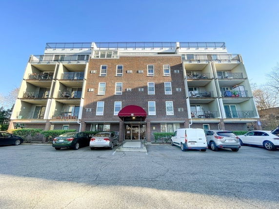 Front view of a multi-story brick apartment building with balconies.