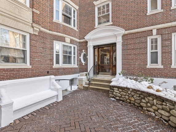 Front view of a brick building entrance with steps and arched doorway.