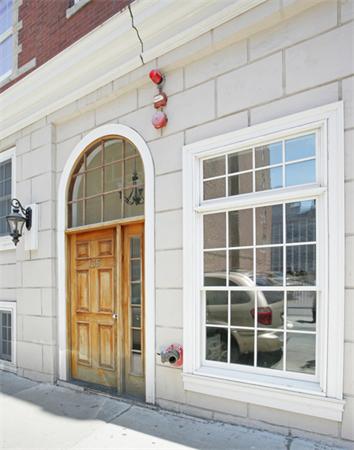 Front view of a building entrance with wooden door and large window.