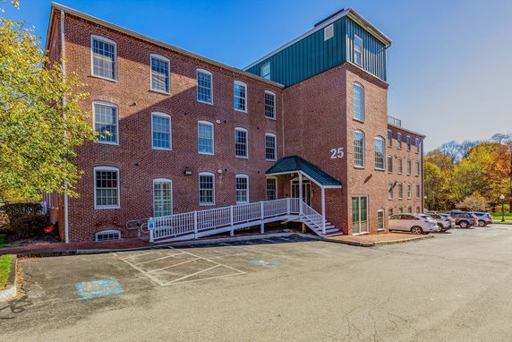 Front view of a multi-story brick building with a ramp and parking area.