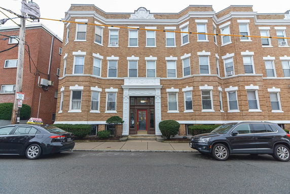 Front view of a multi-story brick apartment building with bay windows.