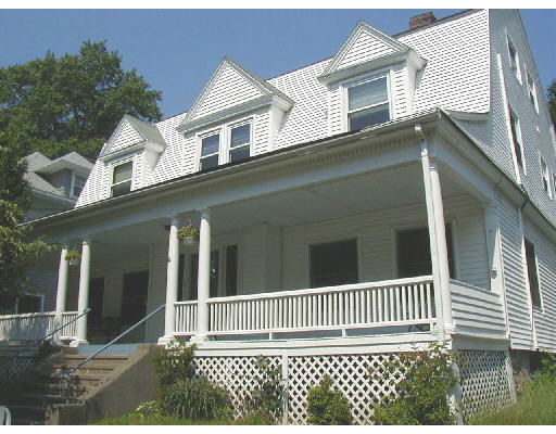 Front view of a white two-story house with a porch and gabled roof.