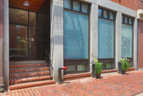 Front view of a building entrance with brick steps and large windows.