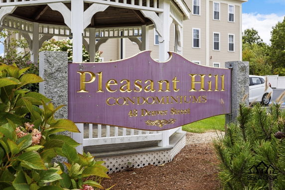 Front view of Pleasant Hill Condominiums sign with partial gazebo and building in the background.